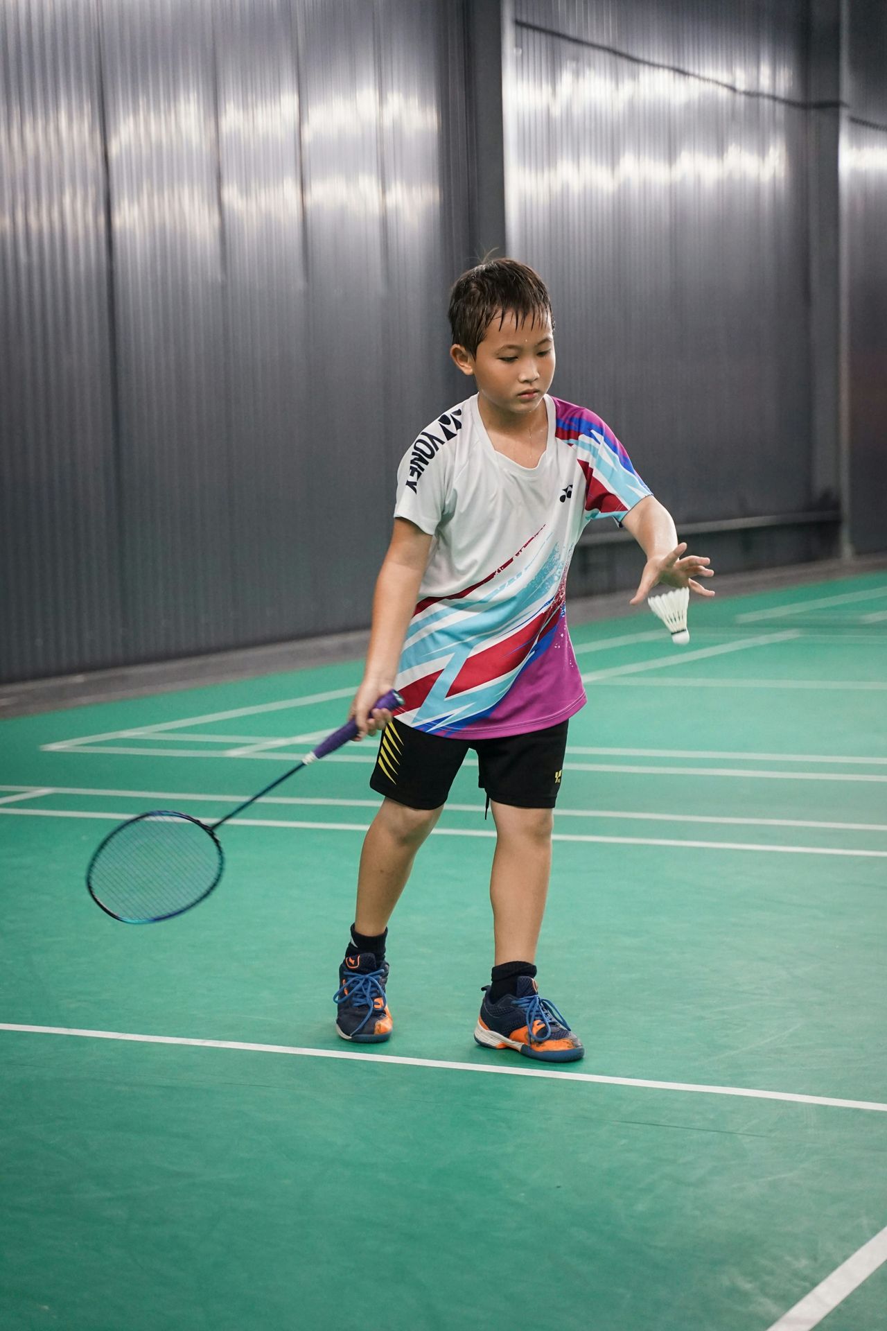 a young boy holding a tennis racquet on a tennis court
